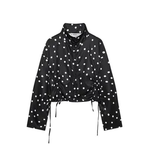 Primer plano de chaqueta negra de lunares con cuello alto y dobladillo fruncido