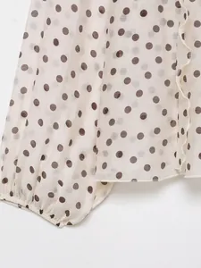 Detailweergave van het polkadotpatroon en de geplooide lantaarnmouwen van dit beige overhemd