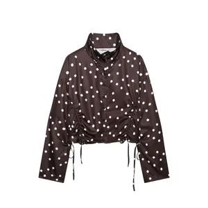Vista detallada de chaqueta marrón de lunares con cuello alto y laterales fruncidos