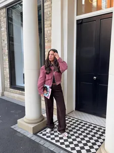 Lifestyle weergave van een roze corduroy jas met leren kraag details op een model