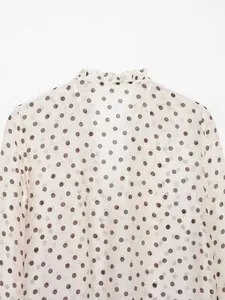Gedetailleerde macro-weergave van de elegante ruffelkraag op een witte blouse met stippen