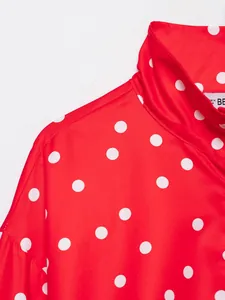 Vista detallada de la tela roja con lunares blancos y diseño de cuello alto para mujer