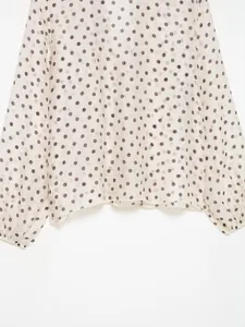 Detail van het polkadotpatroon en de lantaarnmouwen van het damesoverhemd.