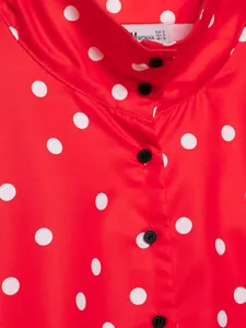 Vista detallada de prenda roja con lunares blancos, cuello alto y botones negros