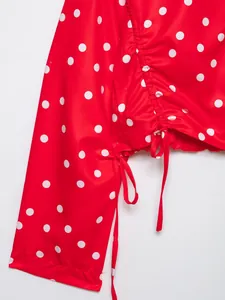 Detalle de una blusa roja con lunares y diseño fruncido con cordones ajustables