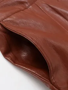 Gros plan des coutures fines et de la texture d'une veste en similicuir marron au détail.