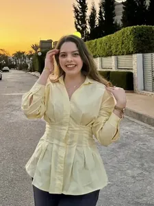 Camicia gialla a maniche lunghe con colletto polo e vita a peplo plissettata da donna