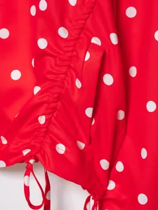 Primer plano de tela roja con lunares blancos, cordón fruncido y detalle de bolsillo lateral