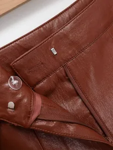 Détail rapproché du short en cuir marron avec fermeture éclair et bouton à la taille