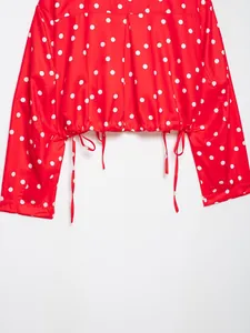 Detalle de chaqueta roja con lunares blancos y un dobladillo con cordón ajustable