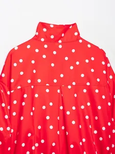 Primer plano de una chaqueta roja de cuello alto con lunares blancos y detalles plisados atrás