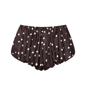Primer plano de los elegantes pantalones cortos plisados marrones con lunares blancos