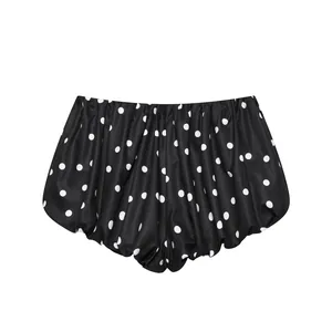Vista detallada de pantalones cortos tipo bombacho negros con lunares y pliegues