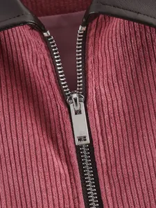 Detailopname van een metalen rits op een roze corduroy jasje met een leren kraag