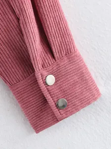 Detailopname van een roze corduroy jasmanchet met twee zilverkleurige metalen drukknopen