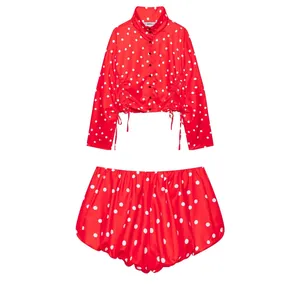 Conjunto de dos piezas rojo con lunares blancos, chaqueta de cuello alto y pantalón.