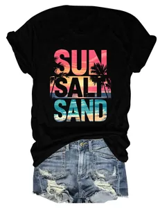 Dettaglio di una t-shirt nera da donna con grafica tropicale 'SUN SALT SAND' al tramonto