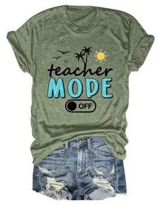 Detalle de camiseta verde militar con gráfico "Teacher Mode Off" y elementos tropicales.