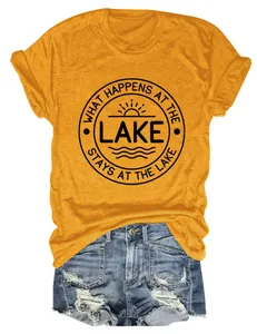 Gros plan du graphique WHAT HAPPENS AT THE LAKE sur un t-shirt jaune moutarde