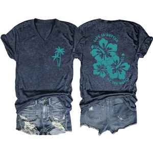 Detail view of navy V-neck tee with palm tree and hibiscus print paired with denim shorts.