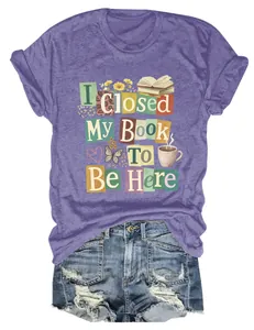 Close-up of purple t-shirt with 'I Closed My Book To Be Here' graphic and denim shorts