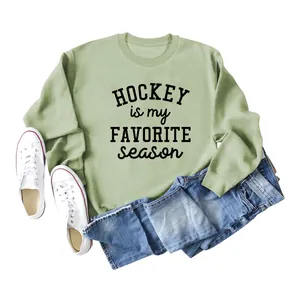 Detailed flat lay of sage green hockey sweatshirt paired with denim jeans and white shoes.