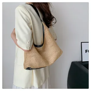 Chic woven hobo bag with black trim carried by model in casual white outfit.