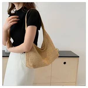 Detail view of large woven mesh tote bag worn over shoulder in a minimalist room