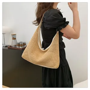 Stylish woven hobo bag with white trim shown on a model's shoulder in a lifestyle setting.