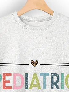 Detail view of a grey pediatric nurse sweatshirt featuring colorful distressed lettering
