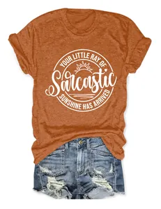 Detail van een oranje T-shirt met "Little Ray of Sarcastic Sunshine" print en spijkerbroek.