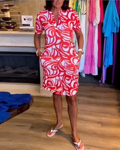 Full view of a woman wearing a vibrant red and white printed V-neck dress with side pockets