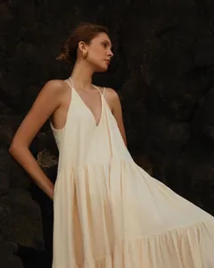 Detailed view of a cream pleated summer beach maxi dress featuring thin straps and gold accents