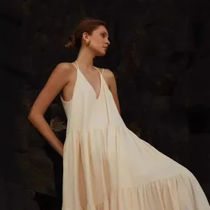 Elegant cream pleated tiered maxi dress with a halter neck for summer beachwear.