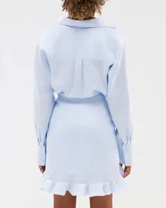 Back view of light blue shirt dress featuring long sleeves and delicate ruffle hem detail