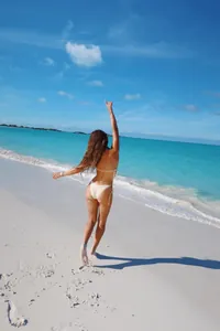 Femme en bikini blanc à paillettes sexy sur une plage tropicale vue de dos