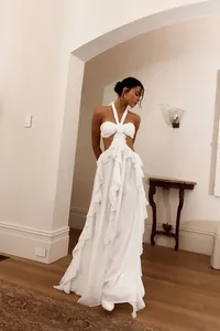 Dettaglio di un abito lungo bianco con scollo all'americana, volant e ritagli in vita