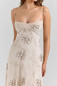 Close-up of elegant floral beadwork and embroidery on a cream slim slip dress