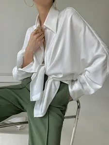 Vue détaillée d'une élégante chemise en satin à rayures blanches avec un nœud et un fini soyeux.