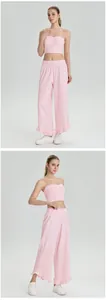Model draagt lichtroze tweedelige set met wijde broek met ruches en bandeau-top
