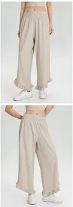Gedetailleerde weergave van beige sportbroek met wijde pijpen en elegante ruffelzoom.