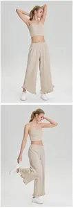 Model draagt een beige strapless top en een wijde sportbroek met ruches in de studio.