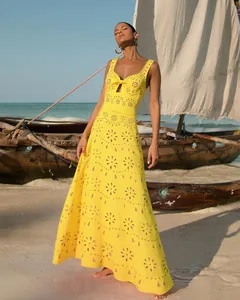 Close-up of yellow hollow-out maxi dress with floral laser-cut patterns on the beach