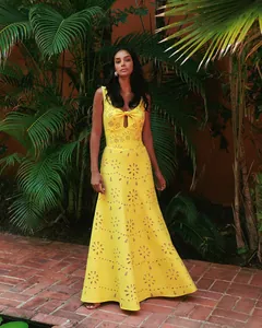 Elegant yellow hollow-out eyelet maxi swimwear cover-up dress in tropical garden setting.