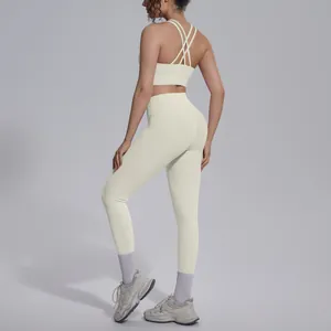 Back view of cream cross-back sports bra and high-waisted yoga leggings on model.