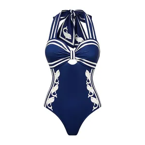 Détail d'un maillot de bain une pièce licou bleu marine avec motifs poissons blancs.