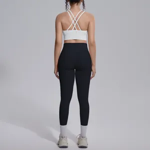 Back view showing cross-strap detail of white sports bra and black high-waist yoga leggings