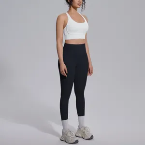 Side view of a woman wearing a white sports bra and black high-waisted yoga leggings.