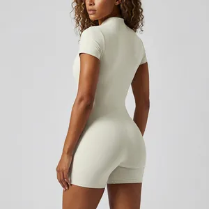 Vista trasera de un mono de yoga beige de manga corta con cuello alto y corte ajustado