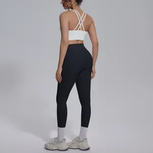 Rear view of a white cross-back sports bra and black high-waisted yoga leggings